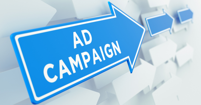 Text graphic reading "Ad Campaign" on a blue arrow, representing increased sales through active advertising.